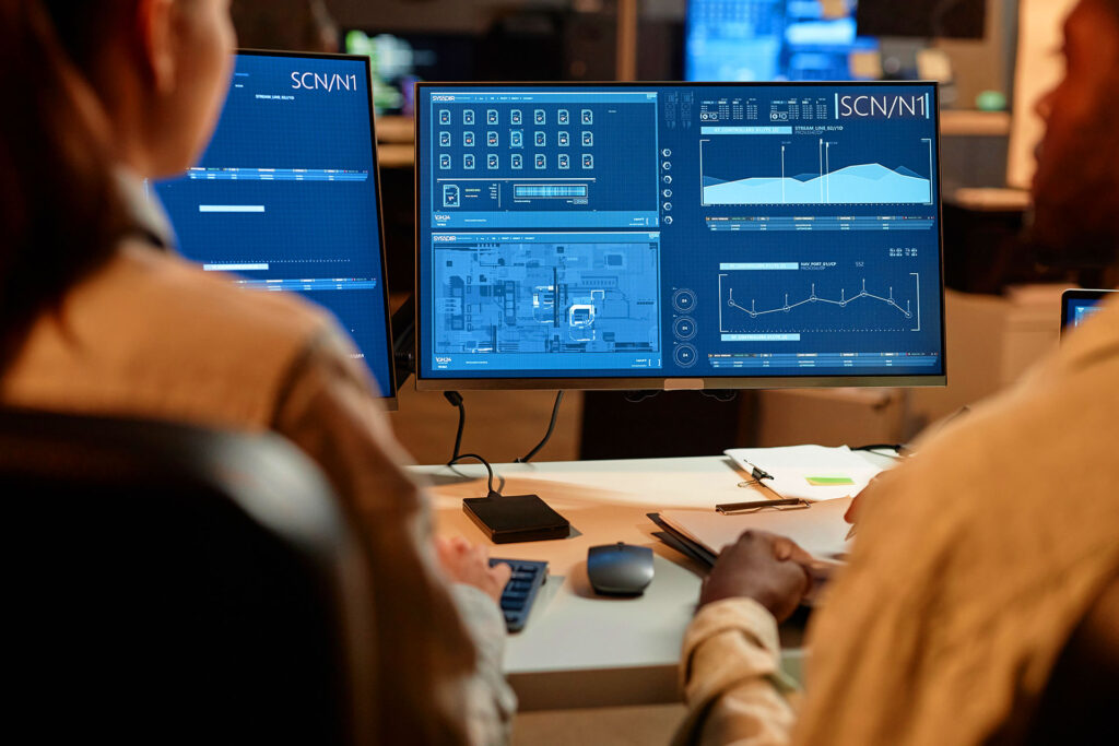Professionals analyzing cybersecurity dashboard on office monitor