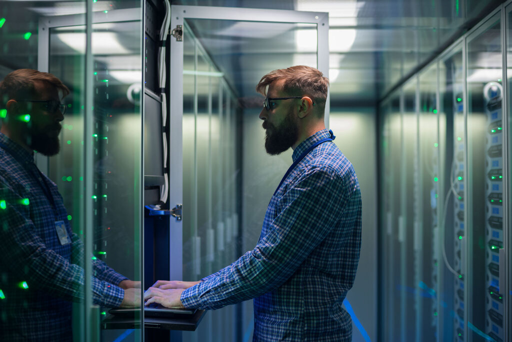 IT technician working in server room with laptop